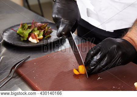 Closeup Of Chef Hands Cutting Tomaos Preparing Salad In A Restaurant Kitchen