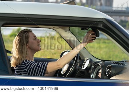 Happy Female Car Owner Enjoy Driving Adjust Rear View Mirror Holding Steering Wheel. Cheerful Woman 