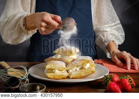 Powdered Sugar Sprinkling From A Sieve In Womans Hand, Cooking Sweet Puff Pastry With Cream Icing Su