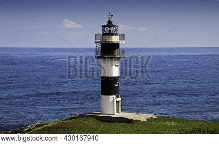 View Of The Pancha Island Lighthouse In Ribadeo, Galicia. With The Blue Sea In The Background.