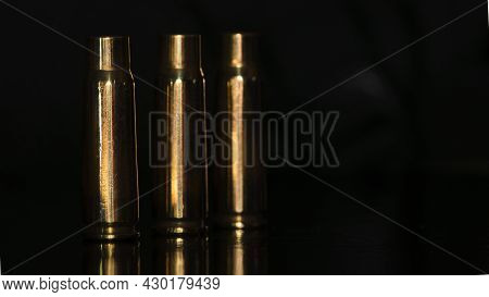 Spent Cartridges On A Black Background. Three Empty Cartridge Cases Are Lined Up Side By Side. Close