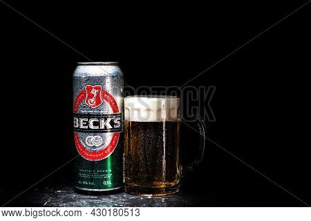 Can Of Beck`s Or Becks Beer And Beer Glass On Dark Background. Illustrative Editorial Photo Shot In 