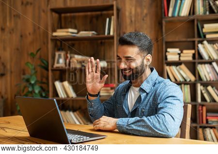 Positive Smart Indian Freelancer Guy Working On Laptop At Home Office, Holding Virtual Meeting, Mult
