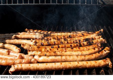 Roasted Bbq Sausages With Grillmarks Cooking On Grill Barbecue With Smoke. Outdoor Summertime Meal P