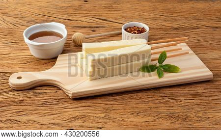 Rennet Or Coalho Cheese On A Wooden Board With Sugar Syrup And Pepper.