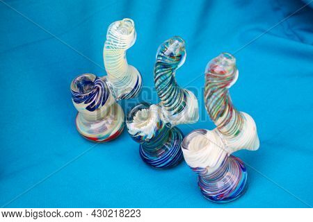 Glass Pipe Or Bong For Marijuana Smoking On A Blue Fabric Background