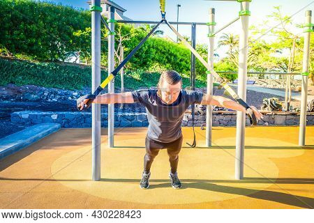 Sport Workout Of Caucasian Men Making Trx Training On Outdoor Sports Gound
