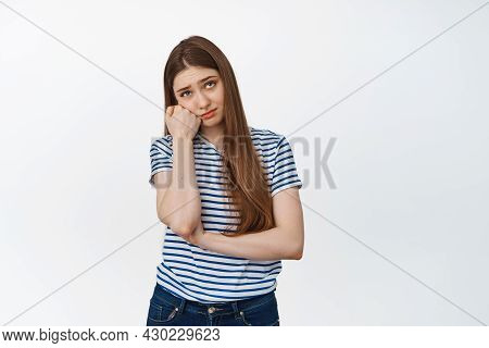 Sad And Bored Young Woman Looking Up, Leaning Head On Arm, Standing Against White Background Unamuse