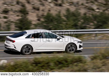Novosibirsk, Russia - August 08, 2021:   
White Kia K5 Driving Fast On Freeway In Highlands On Summe