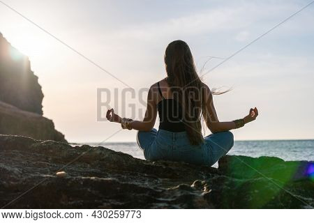 Young Woman With Long Hair In Black Swimsuit And Boho Style Braclets Practicing Outdoors On Yoga Mat