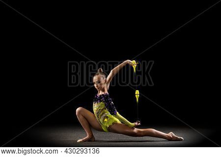 Portrait Of Little Girl, Rhythmic Gymnastics Artist In Bright Stage Costume Isolated On Dark Studio 
