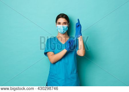 Covid-19, Pandemic And Medicine Concept. Confident Beautiful Woman In Medical Mask And Crubs, Put On
