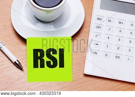 The Wooden Table Has A White Cup Of Coffee, A Pen, A White Calculator, And A Green Sticker With The 