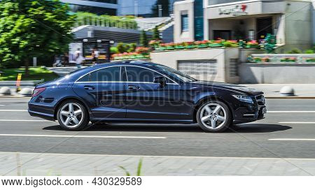 Side View Of A Mercedes-benz Cls In Blue Color. Mercedes Glossy Coupe Rides On The Road. Moscow, Rus