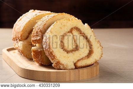 Rocambole, Sliced ​​rocambole Stuffed With Dulce De Leche On A Wooden Tray On A Table. Dark Backgrou