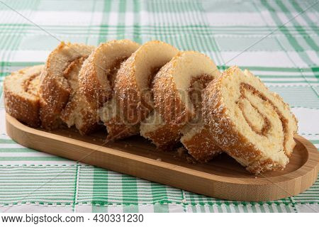 Rocambole, Sliced ​​rocambole Stuffed With Dulce De Leche On A Wooden Tray On A Table With Checkered