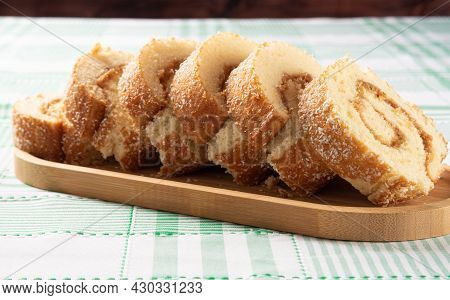 Rocambole, Sliced ​​rocambole Stuffed With Dulce De Leche On A Wooden Tray On A Table With Checkered