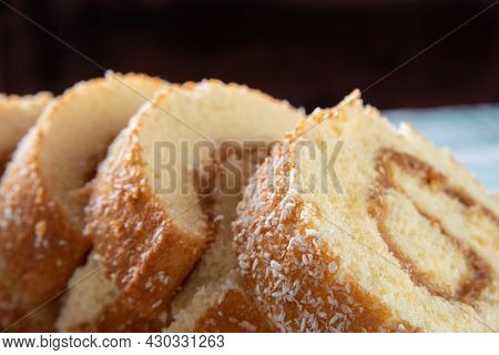 Rocambole, Sliced ​​rocambole Stuffed With Dulce De Leche On A Wooden Tray On A Table With Checkered