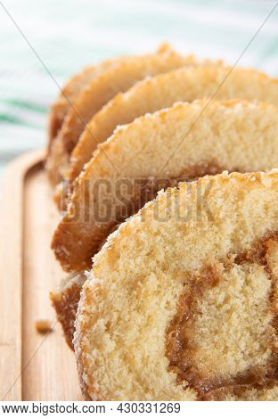 Rocambole, Sliced ​​rocambole Stuffed With Dulce De Leche On A Wooden Tray On A Table With Checkered