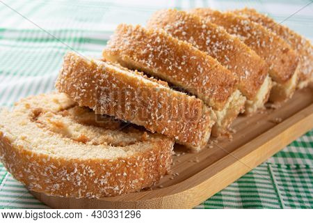 Rocambole, Sliced ​​rocambole Stuffed With Dulce De Leche On A Wooden Tray On A Table With Checkered