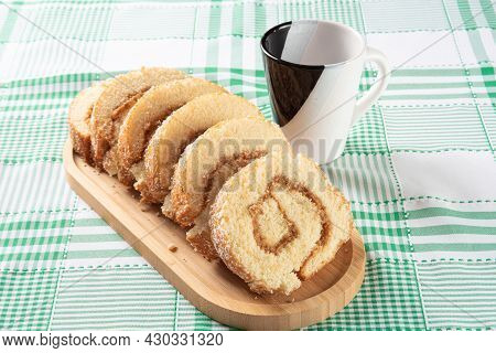 Rocambole, Sliced ​​roacambole Stuffed With Dulce De Leche On A Wooden Tray And A Cup On A Table Wit