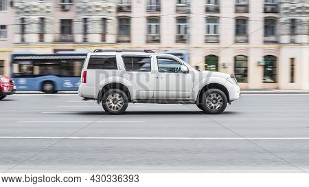 Fast Moving Nissan Pathfinder R51 On The City Road. White Suv Driving On Motorway. Used Auto In Fast