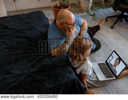 Baldhead Man With Cute Little Child Talk To Woman At Videochat Via Laptop Sitting On Floor