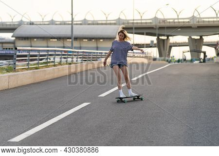 Active Woman Longboarder Of Middle Age Riding Longboard On Empty Road Or Highway. Casual Urban Femal