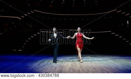 A Girl In A Red Ball Gown And A Guy In A Black Bodysuit. Dance Moves Against A Bright Background Ind