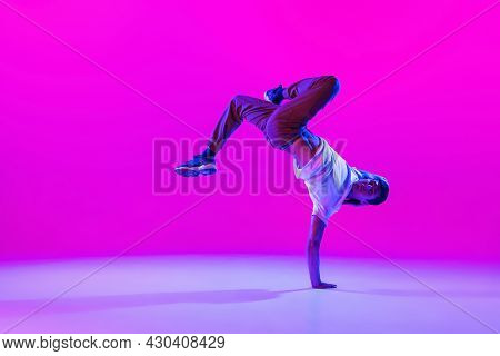 One Young Stylish Man, Break Dancing Dancer Training In Modern Clothes Isolated Over Bright Magenta 