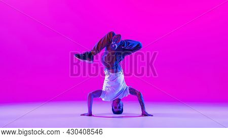 One Young Stylish Man, Break Dancing Dancer Training In Modern Clothes Isolated Over Bright Magenta 