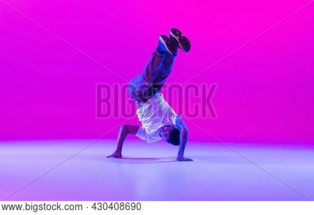 One Young Stylish Man, Break Dancing Dancer Training In Modern Clothes Isolated Over Bright Magenta 