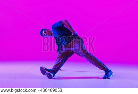 One Young Stylish Man, Break Dancing Dancer Training In Modern Clothes Isolated Over Bright Magenta 