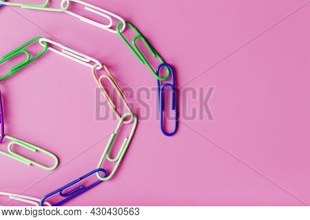 A Chain Of Multi-colored Paper Clips On A Pink Background
