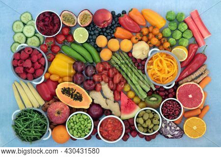 Antioxidant health foods that neutralize free radicals with fruit,  vegetables high in fibre, anthocyanins, lycopene, protein, vitamins, minerals, carotenoids. Healthy food concept. On mottled blue.