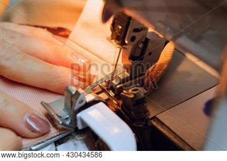 Seamstress Sews Fabric Clothes On A Sewing Machine. Selective Focus On Looper. Limited Depth Of Fiel