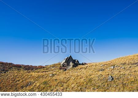 Minimal Autumn Landscape With Pointy Shattered Stone On Orange Hill In Sunlight Under Blue Clear Sky