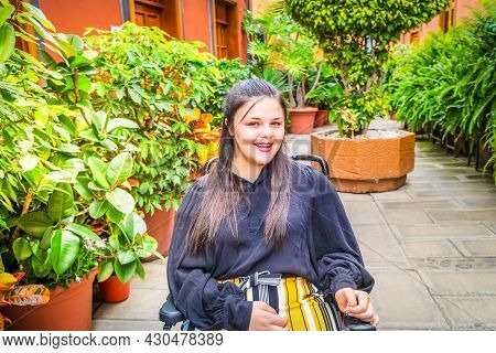 Young Happy Positive Disabled Handicapped Woman In Wheelchair Smiling At Camera While Walking Outdoo