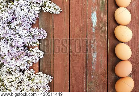 Line Of Rown Eggs Of Domestic Chicken Hens And Lilac Flower Border Frame On Old Red Wood Texture Bac