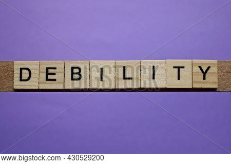 Word Debility In Small Square Wooden Letters With Black Font On A Lilac Background