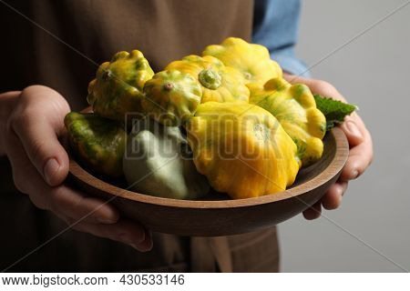 Woman With Wooden Bowl Of Fresh Ripe Pattypan Squashes On Grey Background, Closeup