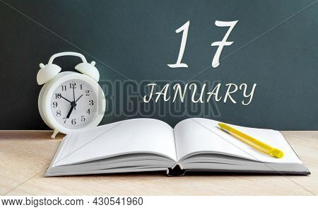 January 17. 17-th Day Of The Month, Calendar Date.a White Alarm Clock, An Open Notebook With Blank P