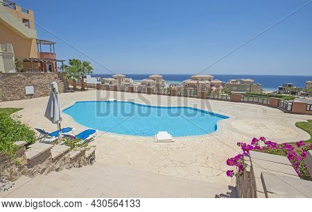 Large Outdoor Swimming Pool At A Luxury Tropical Hotel Resort With Sun Lounger Beds And Sea View
