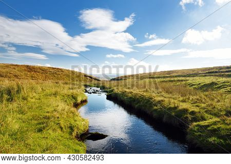 Small Stream Flowing Between Green Lush Pastures In Yorkshire Dales National Park In Northern Englan