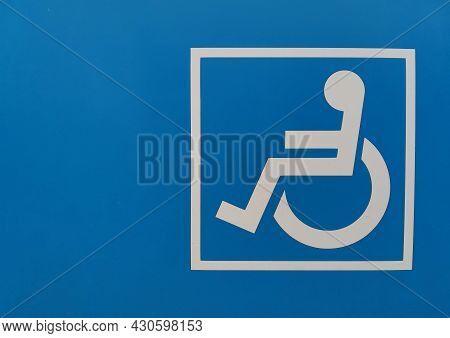 Sign Symbol Of A Disabled Person Sitting In A Wheelchair On A Bright Blue Background