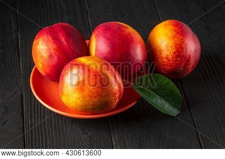 Red Ripe Nectarine Hybrids In Their Ripening Season Lie On Orange Plate Or On A Dark Vintage Table