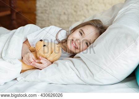 Baby Lying In Bed With Taddy Bear. Little Girl Sleeps With Knitted Toy