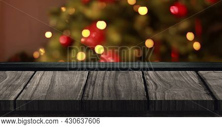 Image of out of focus flickering fairy lights on christmas tree with wooden surface in the foregound. christmas festivity celebration concept digitally generated image.