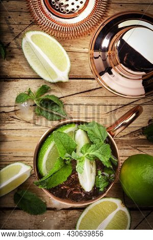 Moscow Mule Cocktails In Copper Mug With Lime, Ice, Ginger Beer, Vodka And Mint. Wooden Background, 