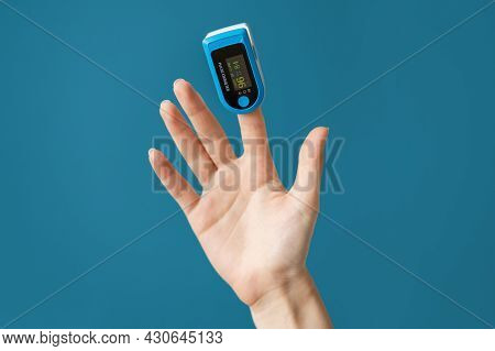 A Woman's Hand With A Pulse Oximeter Placed On The Index Finger. Blue Background. The Concept Of Mea